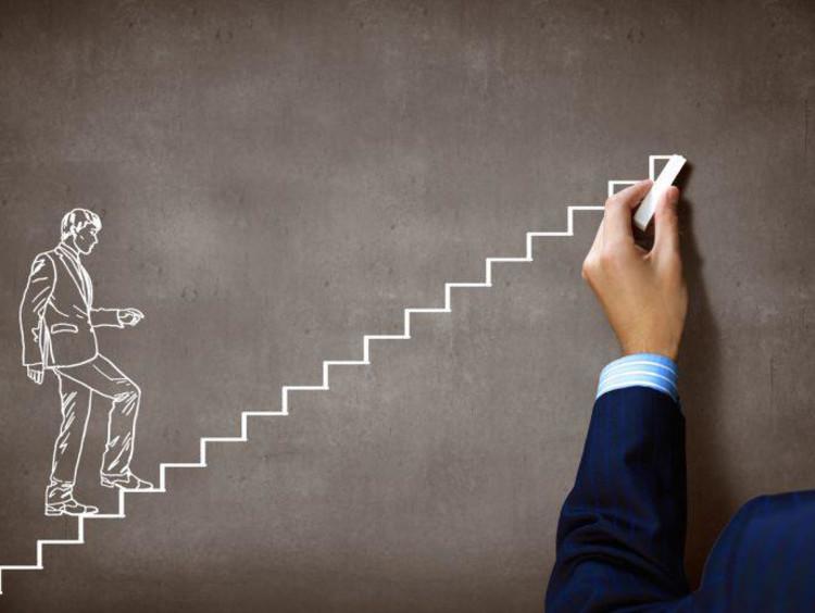 Man draws a businessman walking up stairs on chalkboard