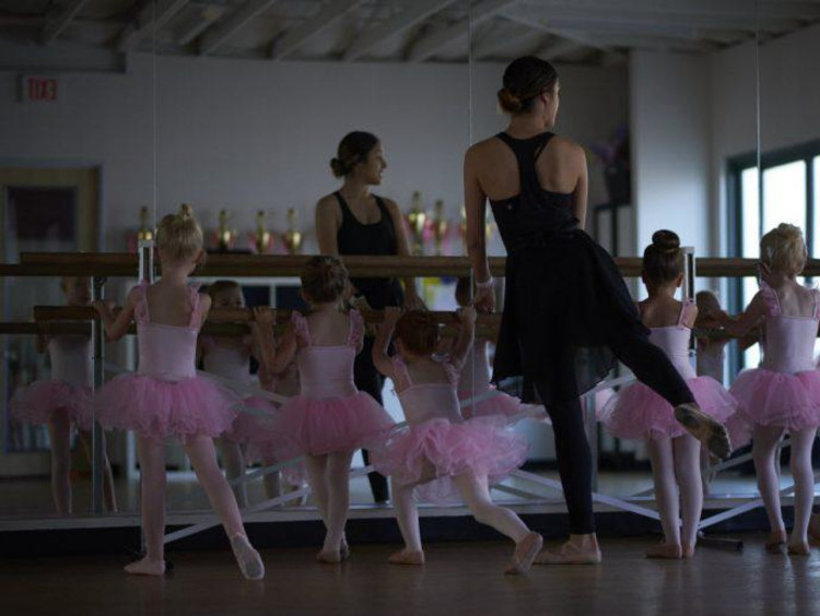 Ballet teacher leads little girls barre movements