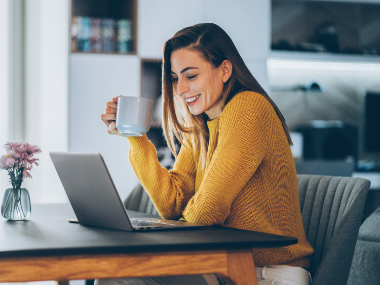 girl holding coffee cup and looking at computer
