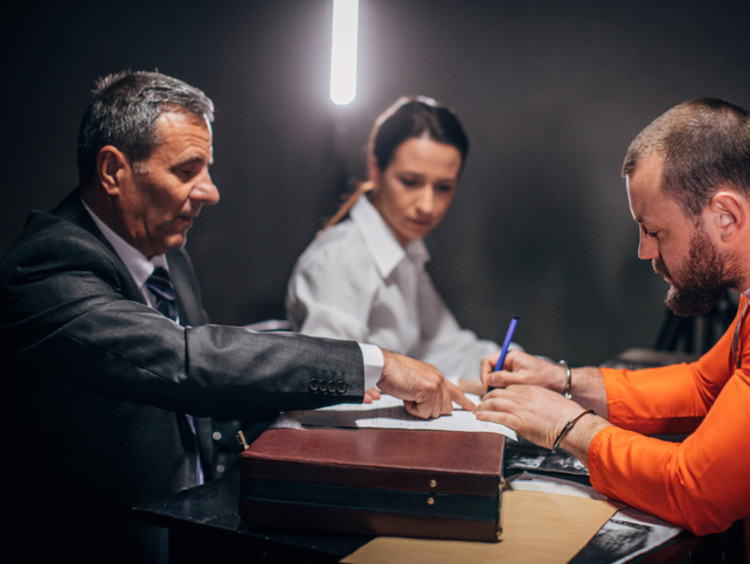 Probation officer shaking hands with convict at desk with paperwork