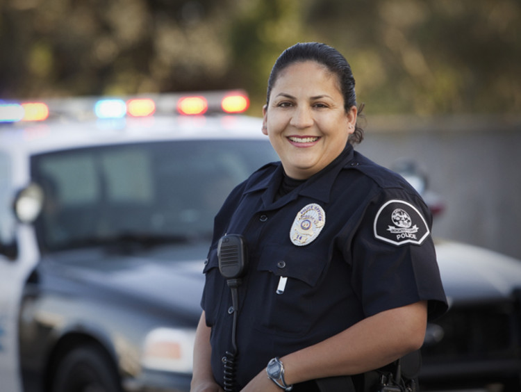 Woman police officer standing beside police vehicle
