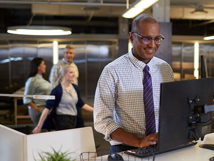 Man smiles are computer station in accounting office setting
