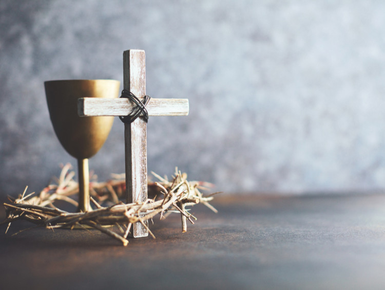 A cross sits with a wine glass and crown