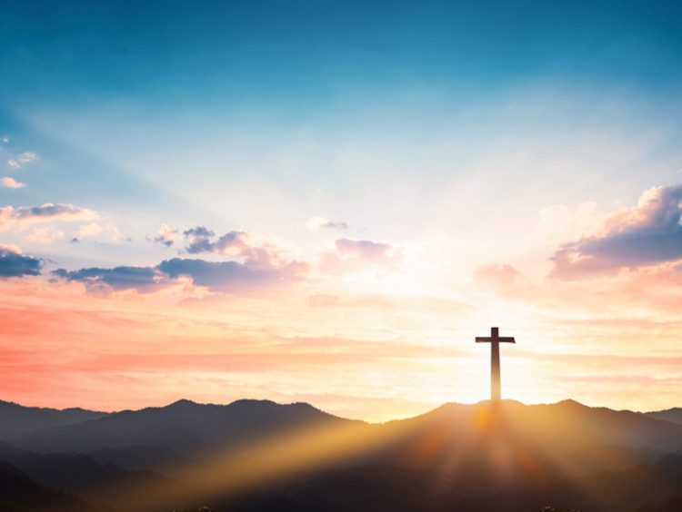 A cross stands in front of behind a beautiful sunset