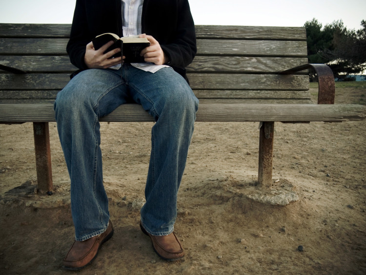 guy sitting on bench with open Bible