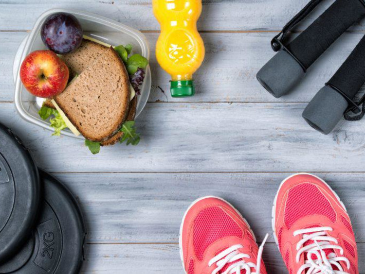 Healthy drink and food in Tupperware next to weights jumprope handles and tennis shoes