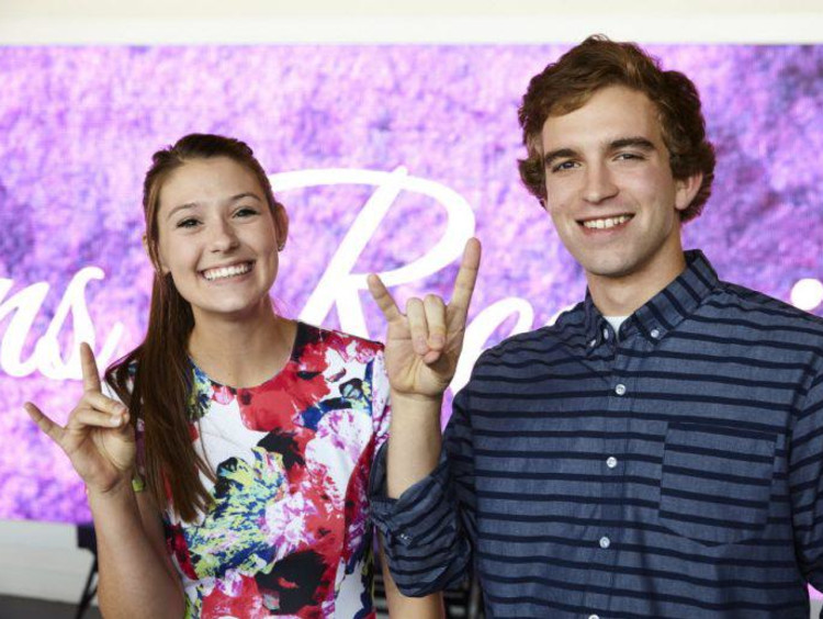 A male and female GCU student doing Lopes Up sign with their hands