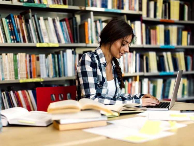 Young female works on PhD coursework in the library