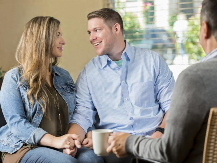 Marriage therapist with a cup of coffee observes couple looking lovingly at each other