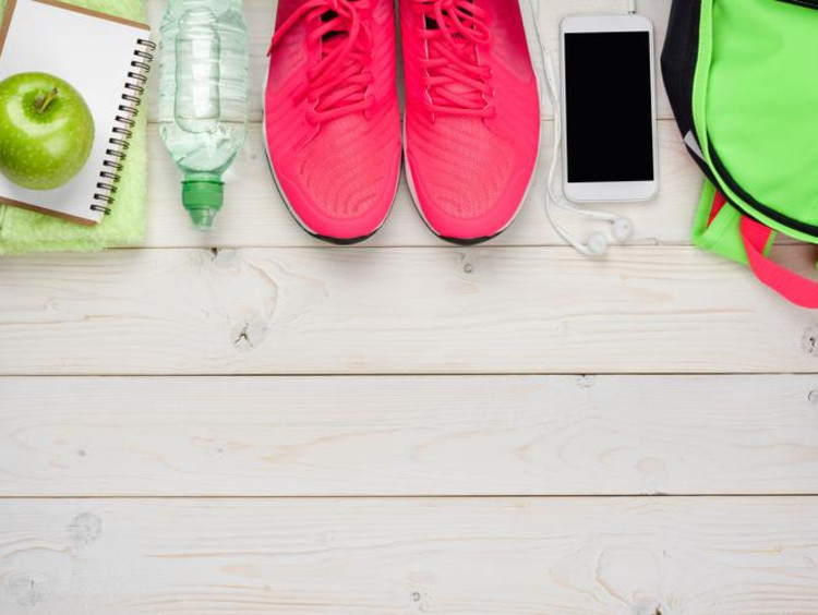 Sports gym bag contents lined up with bright pink athletic shoes in middle