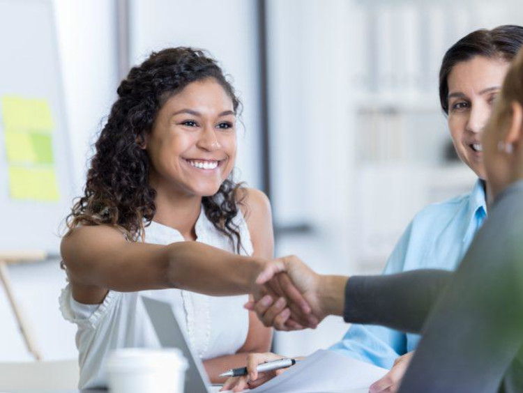 Small group of people shake hands and discuss at a table.