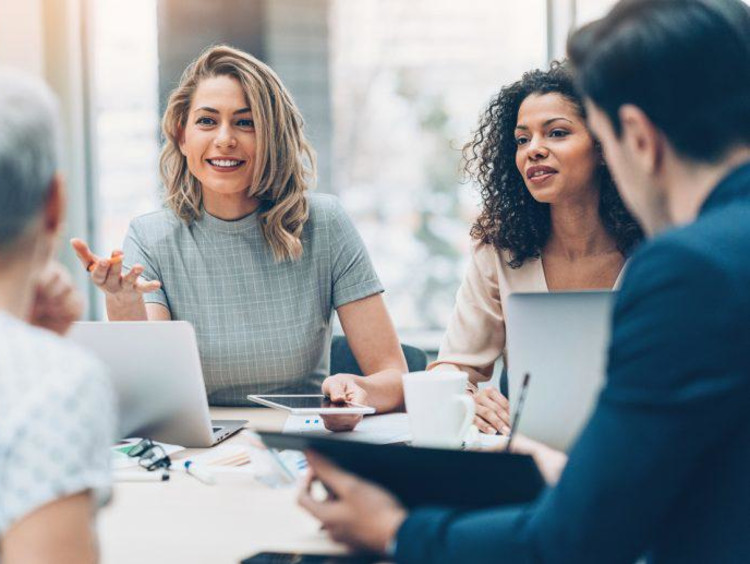 Multicultural group of organizational professionals meet at a table