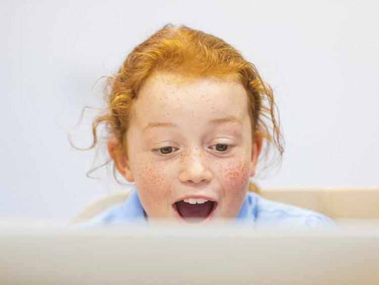 Red-headed girl looks at laptop