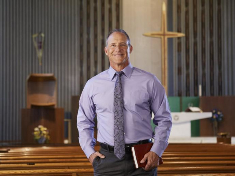 A man in a purple shirt standing in a church