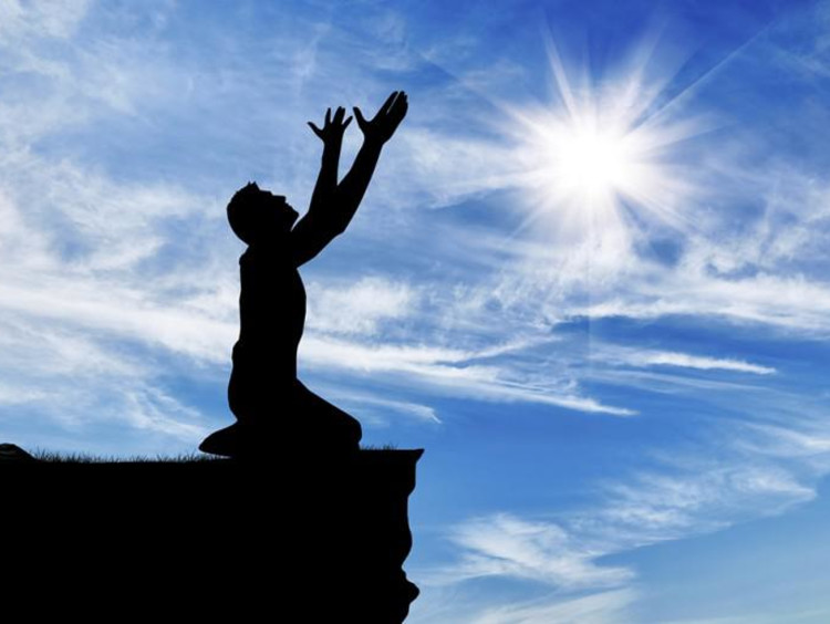 person on knees lifting arms to the sky
