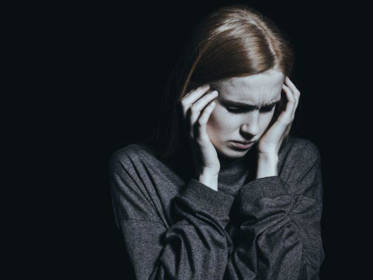 Young girl with PTSD looks scared and covers ears with hands