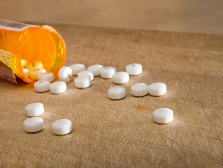 Pill bottle on its side with pills spilling out of it on table