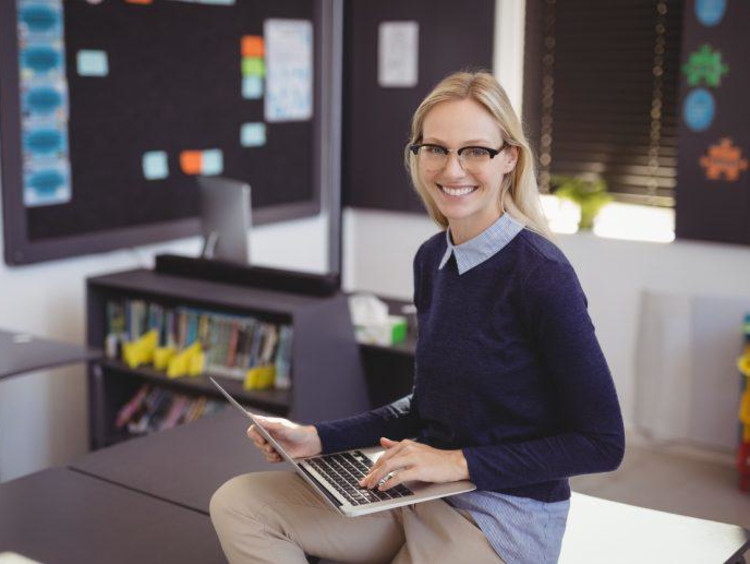 Young adult author smiles with a laptop