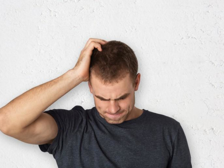 Man scratching head looking down