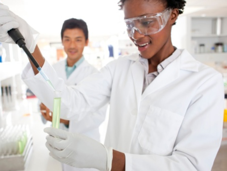 African-American female scientist putting a solution in test tube to use scientific method in a lab
