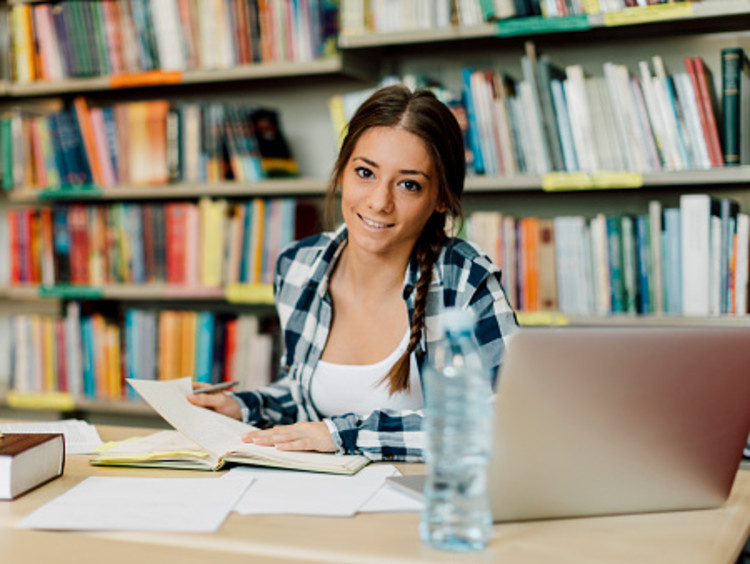 female student studying for college exams in library