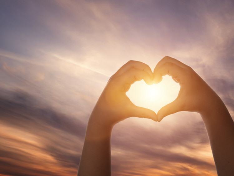 hands forming a heart around the sun