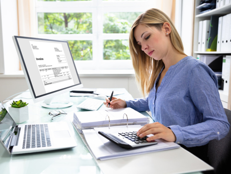 Woman crunches the numbers while analyzing an invoice