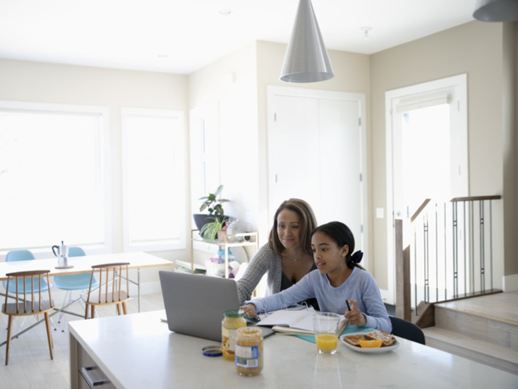 An elementary student doing blended classwork at home with her mother