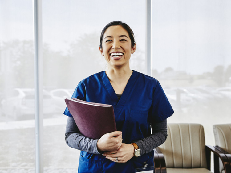 headshot of smiling female nurse holding documents in hospital