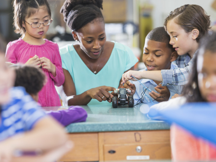 Black STEM teacher doing electricity experiment with students