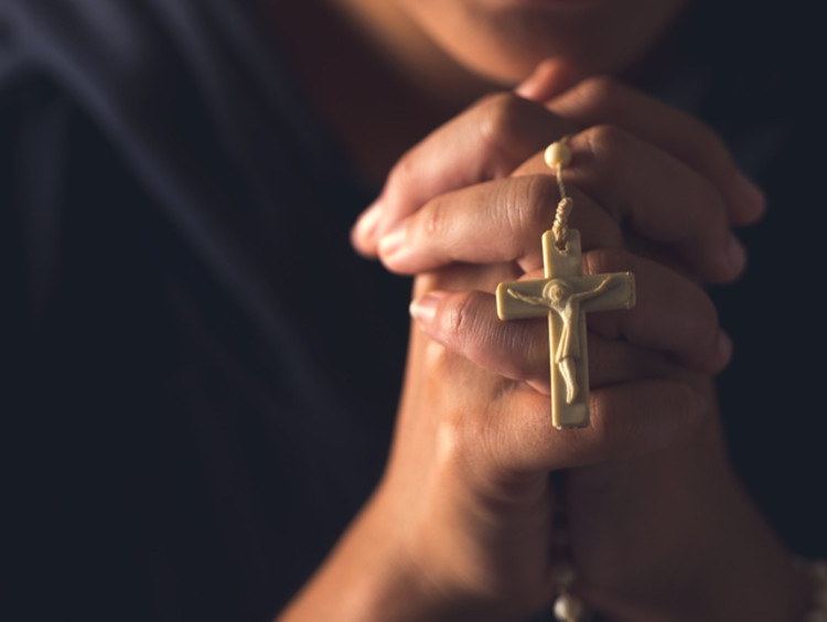 Praying hands clasp rosary