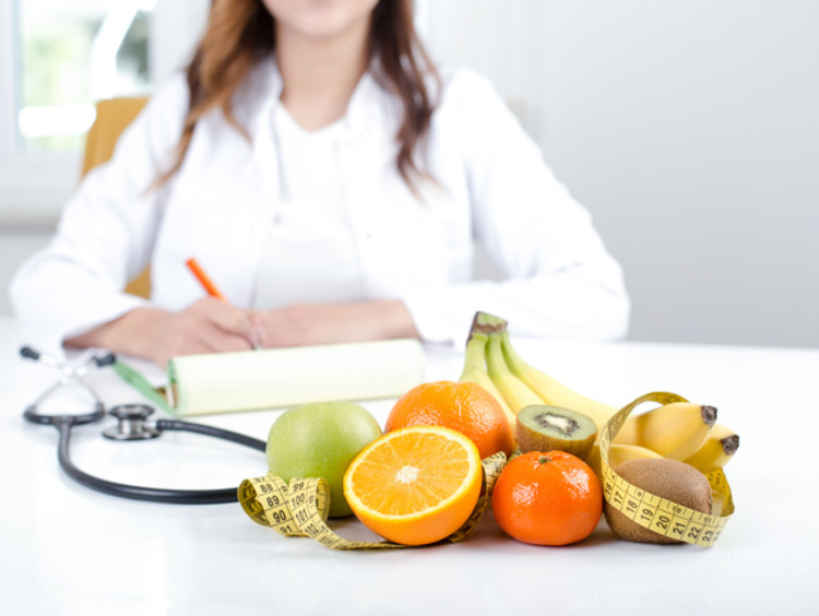 fruits and vegetables on a table and doctor sitting behind desk