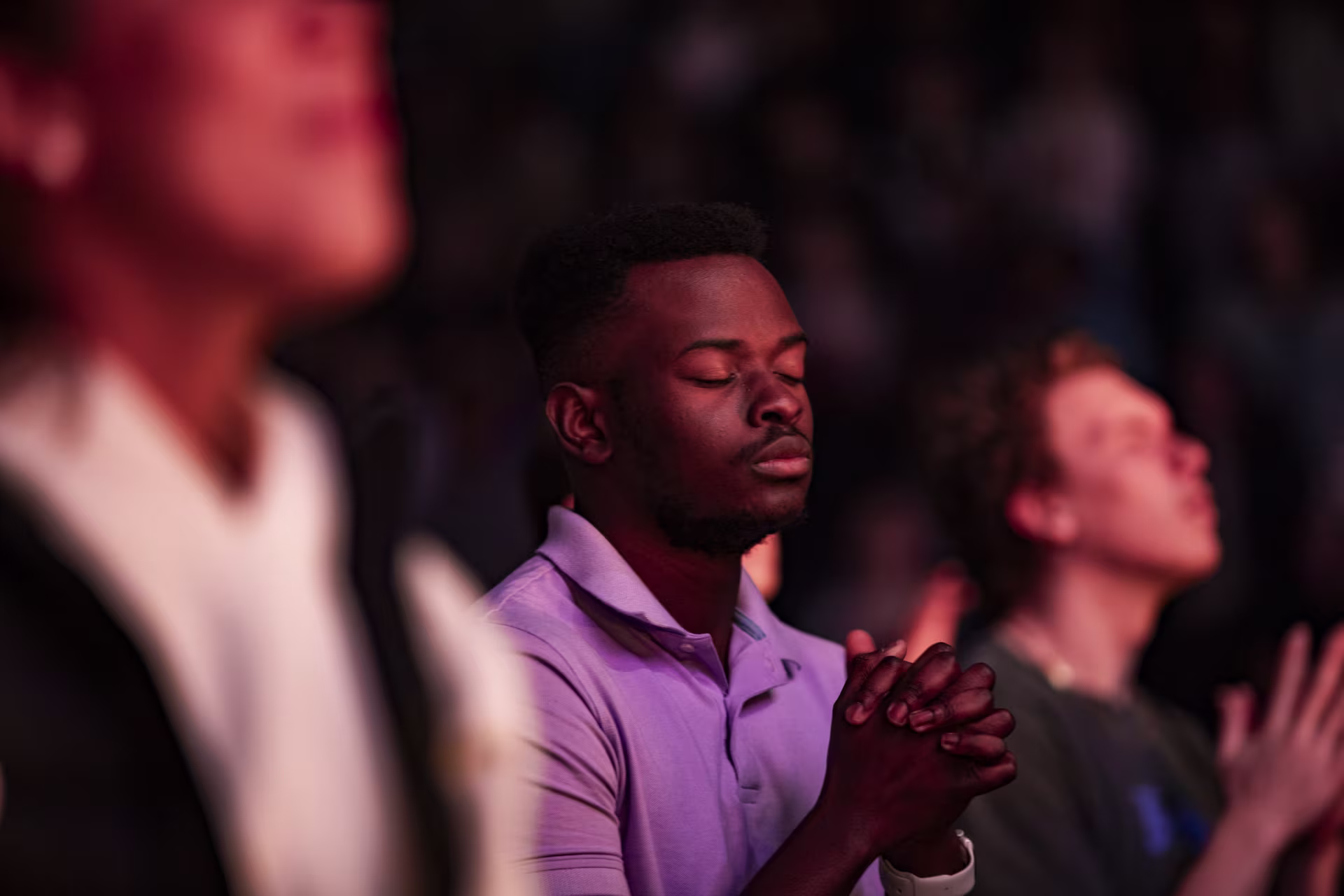Focused shot of male student praying alongside other male students