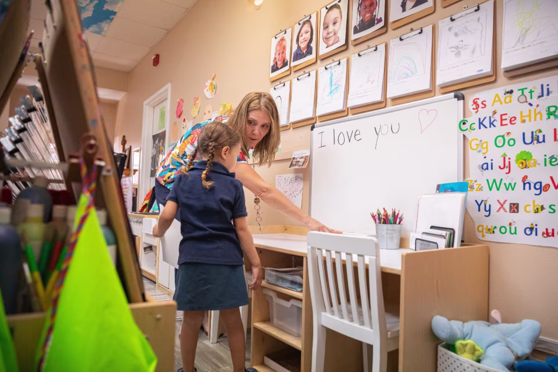 Teacher working with child student on whiteboard in classroom setting