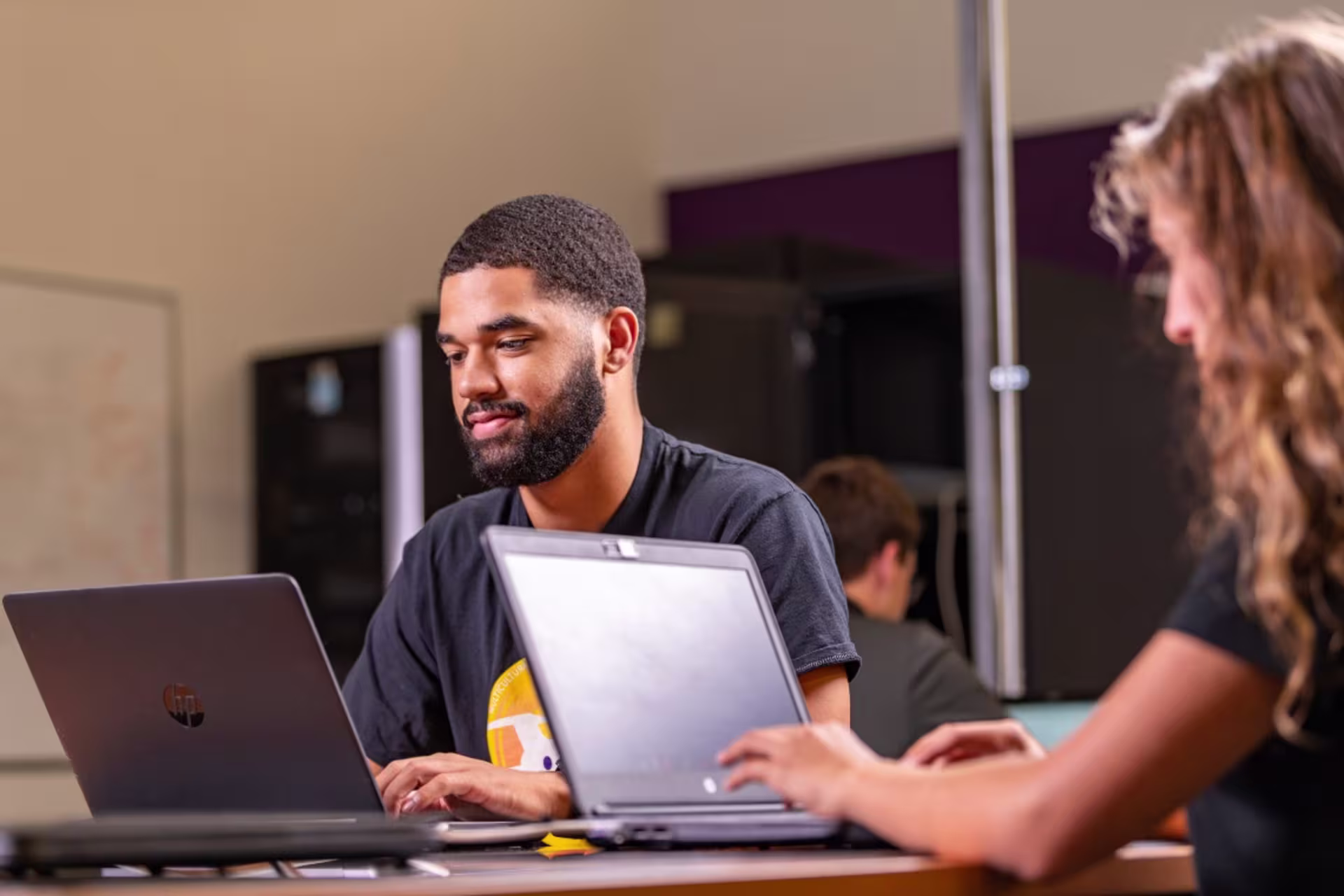 Two GCU students working in classroom on laptops