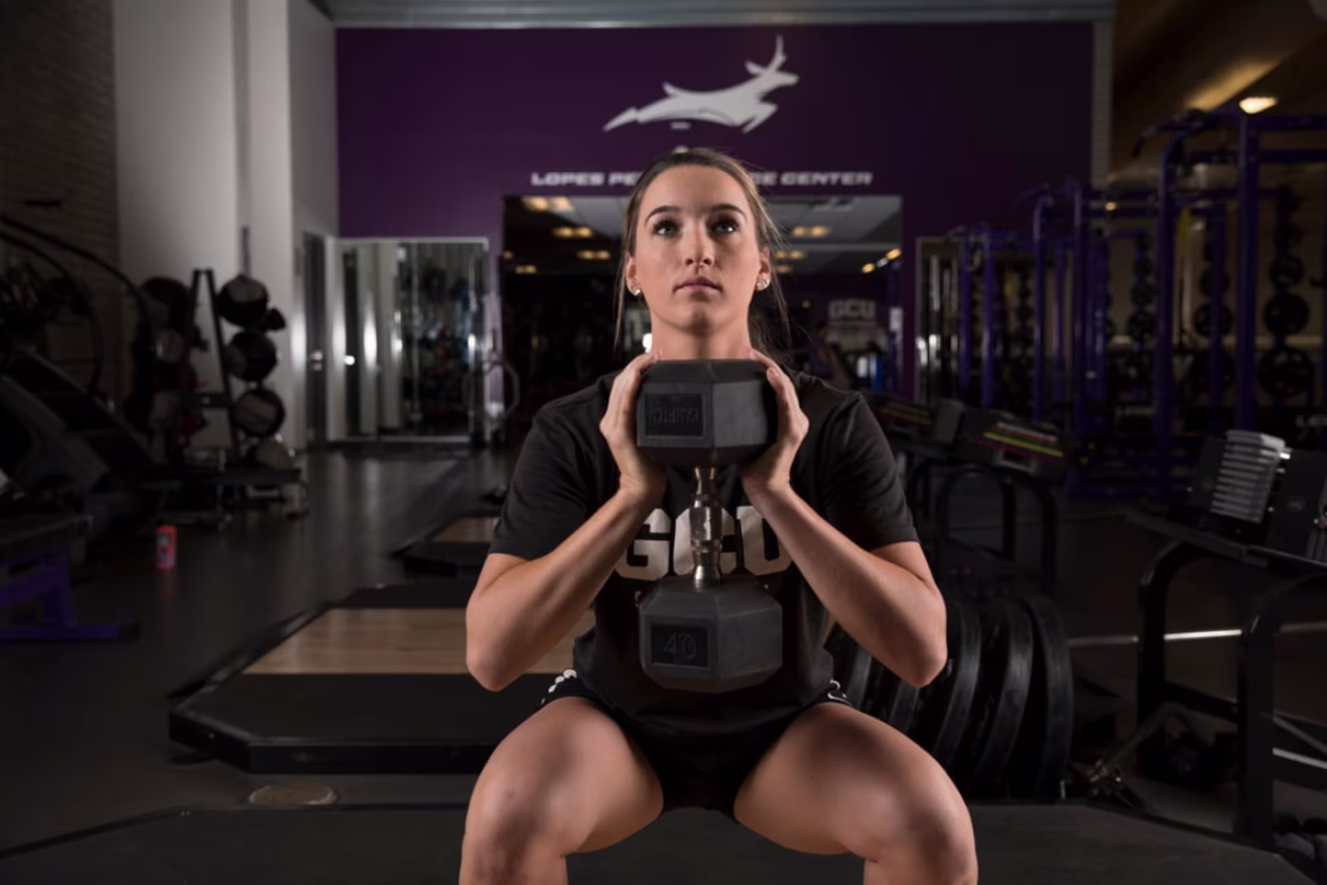 Woman in GCU gym lifting weight while squatting
