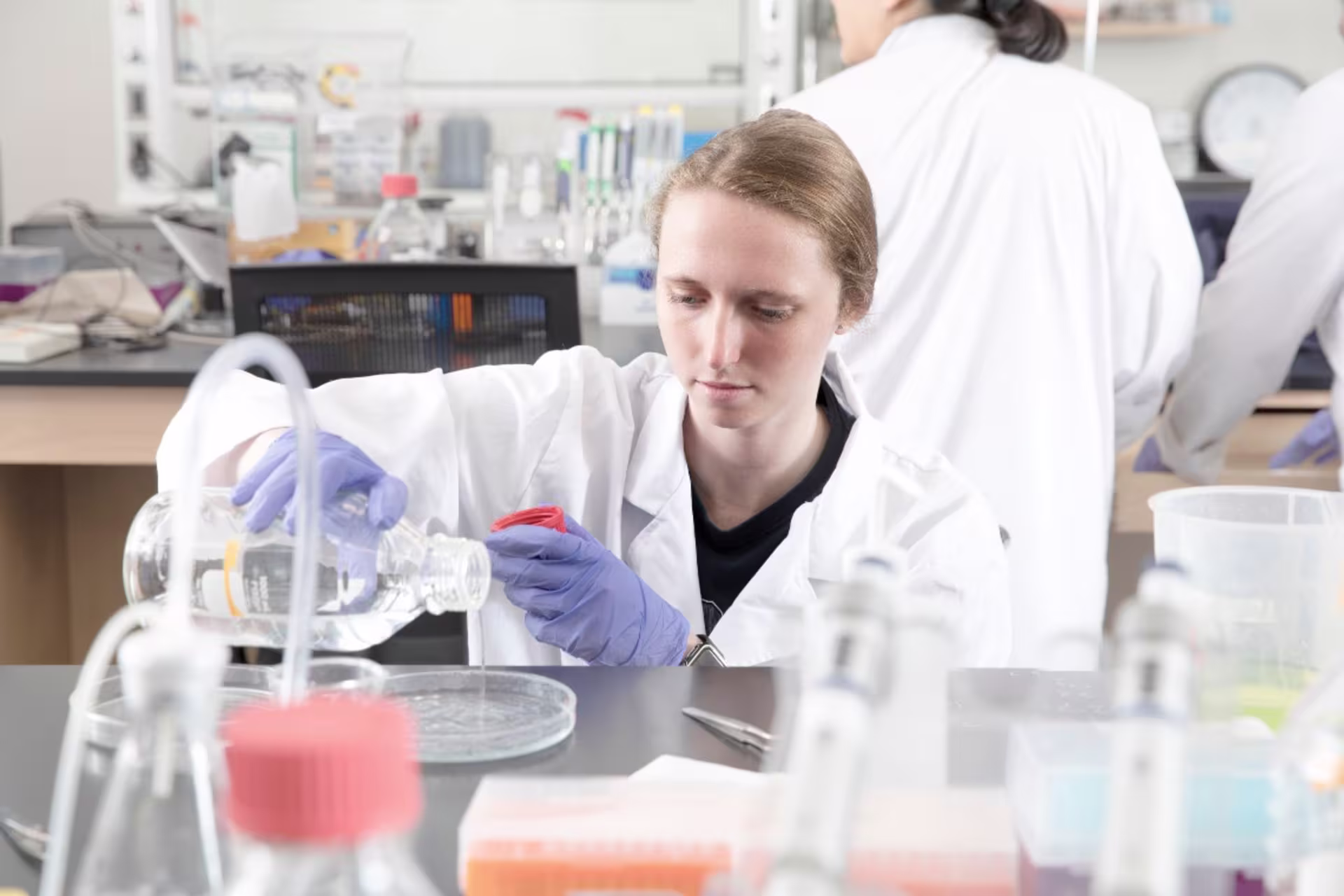 Biomedical engineering students in lab pouring liquid in tray