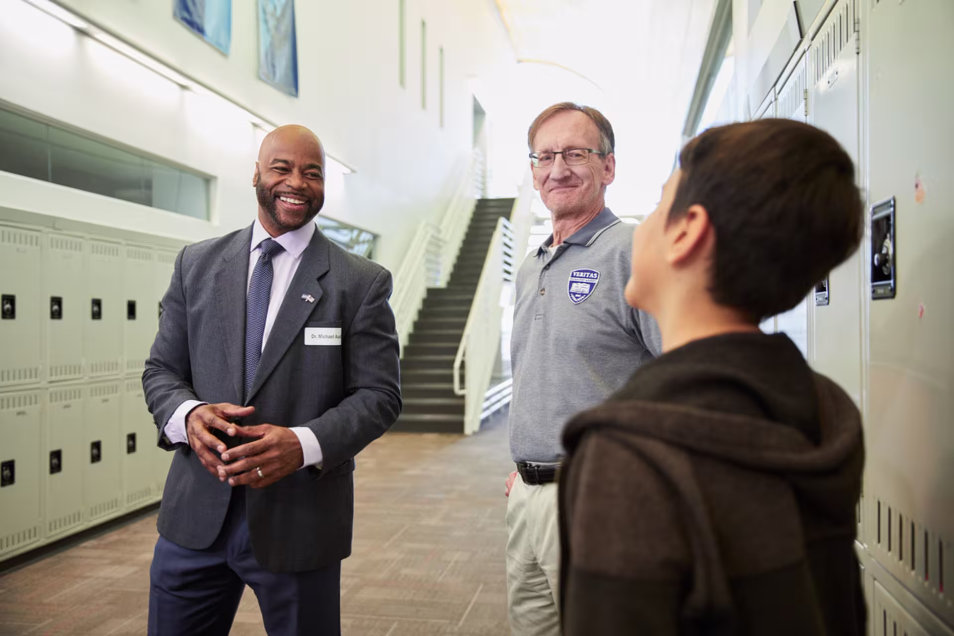 Male EdS professional alongside male educator smiling and speaking with young male student