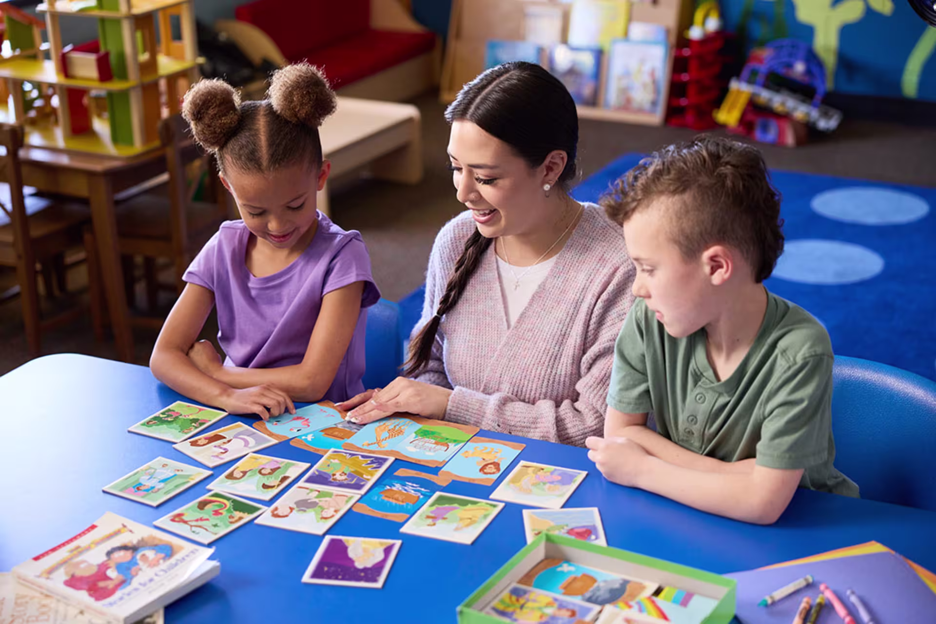Female early childhood education teacher playing cards with young students