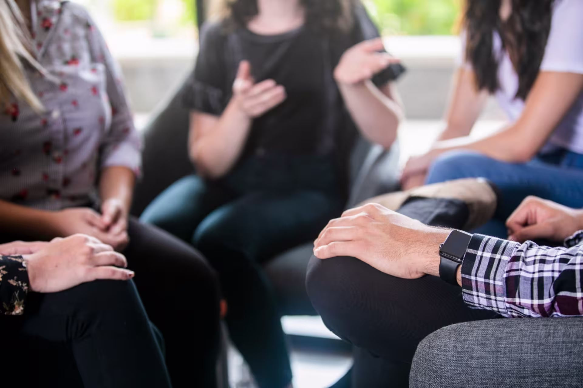 Close up of hands on knees as group sits in a grief circle