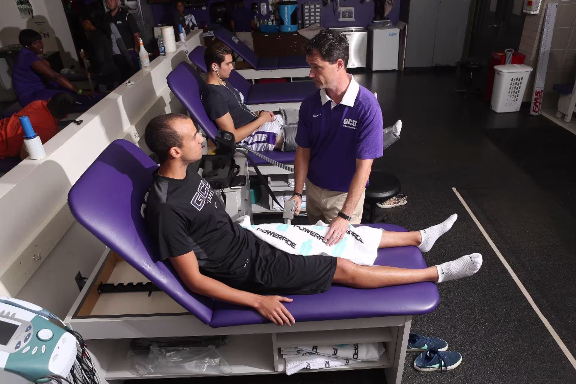 Athletic trainer helping athletes in a training room setting