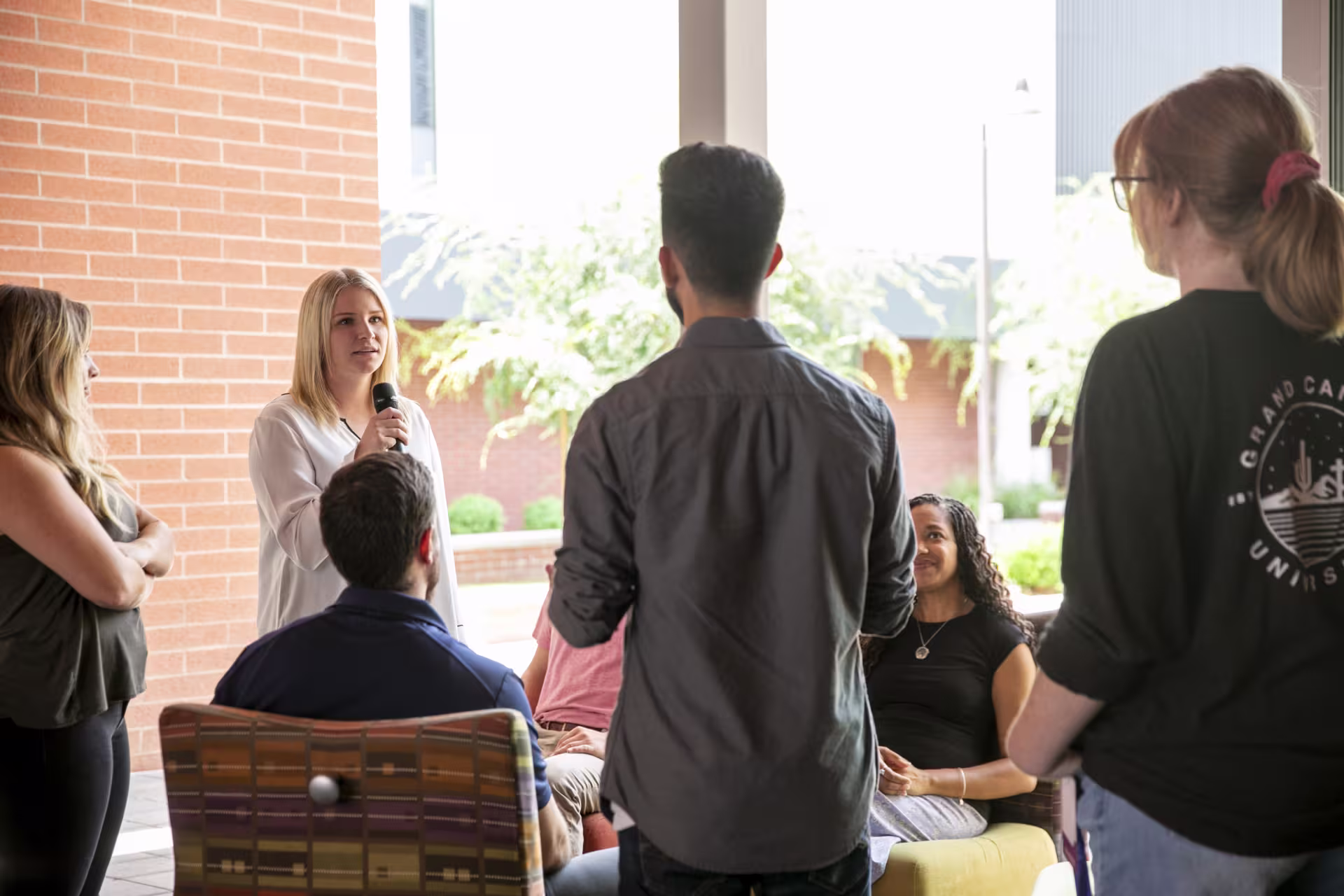 Female addiction counseling instructor speaks with microphone to students.