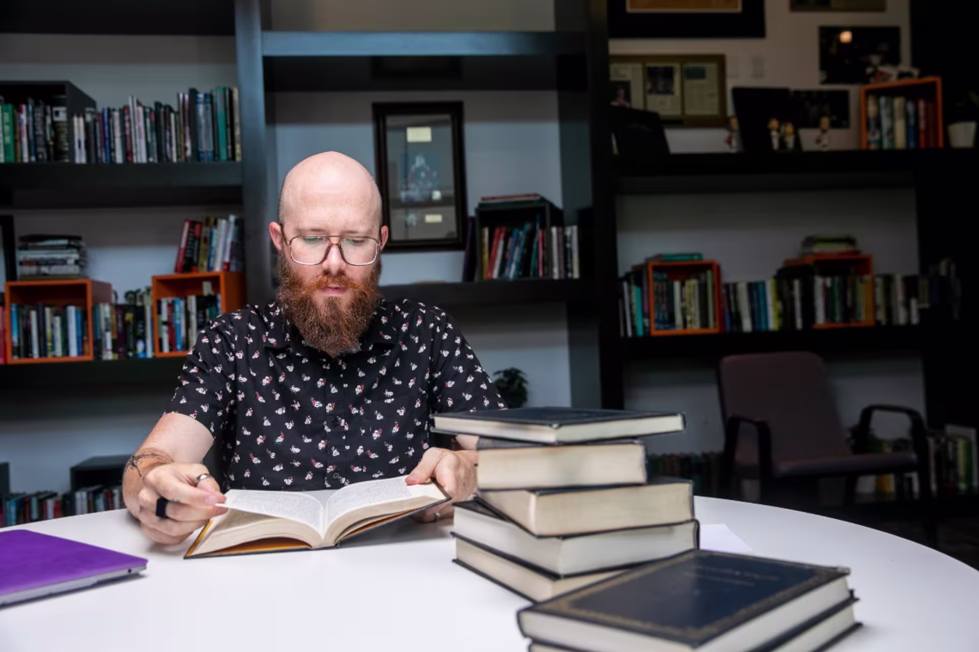 History student sitting at table with a pile of library books