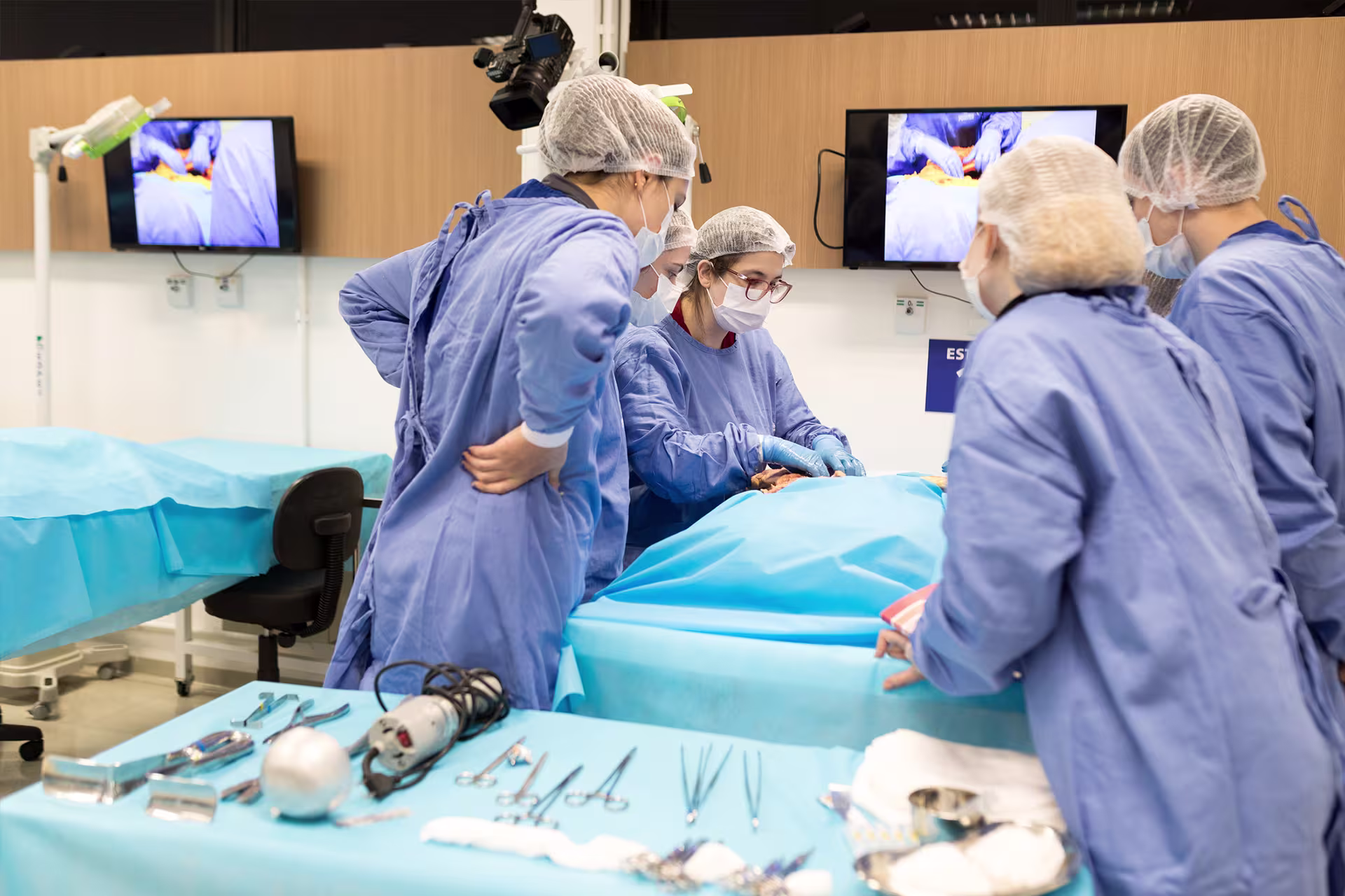 A group of autopsy technicians assisting coroner and reviewing a body in the lab.
