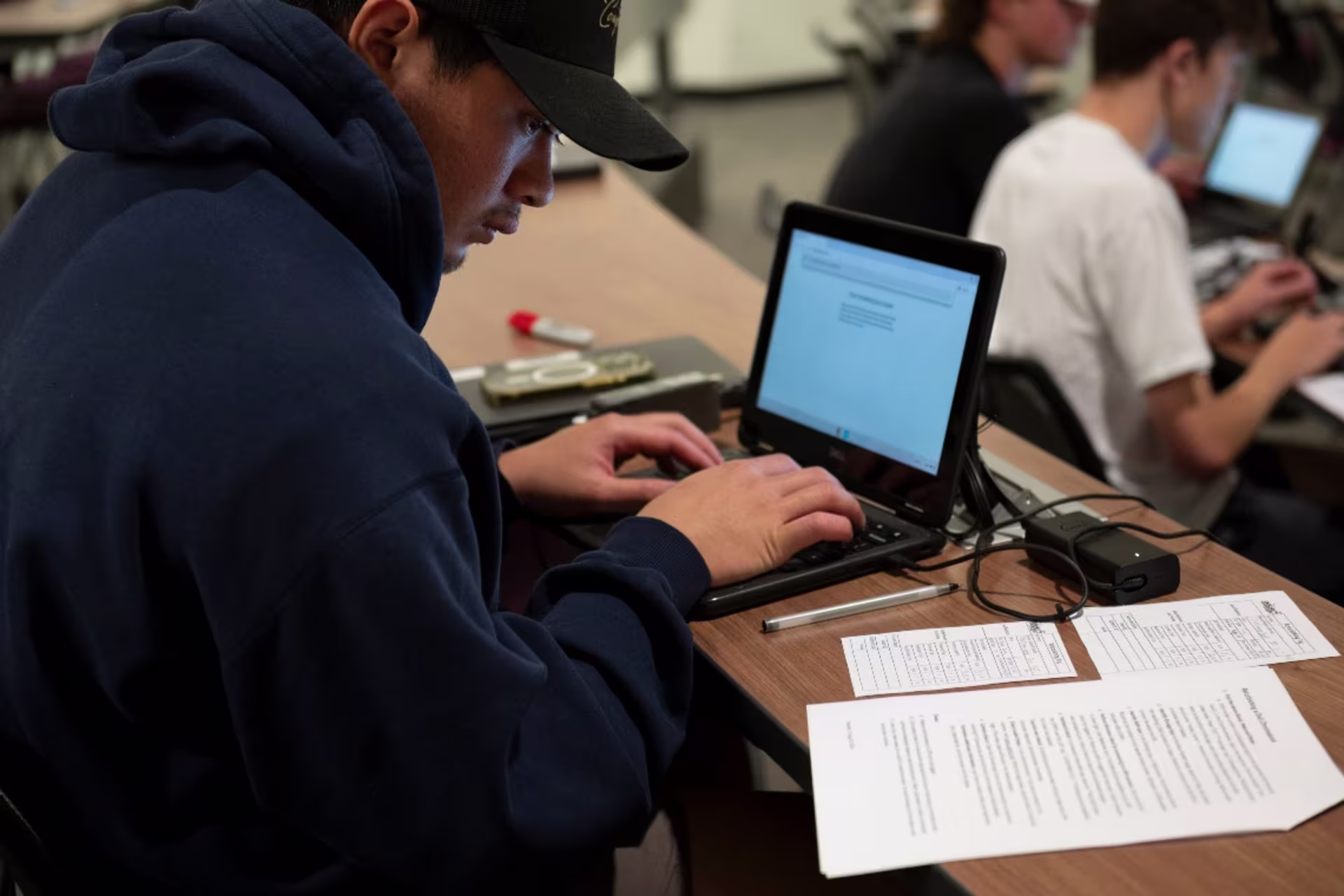 Computer engineering student in class with notes and computer