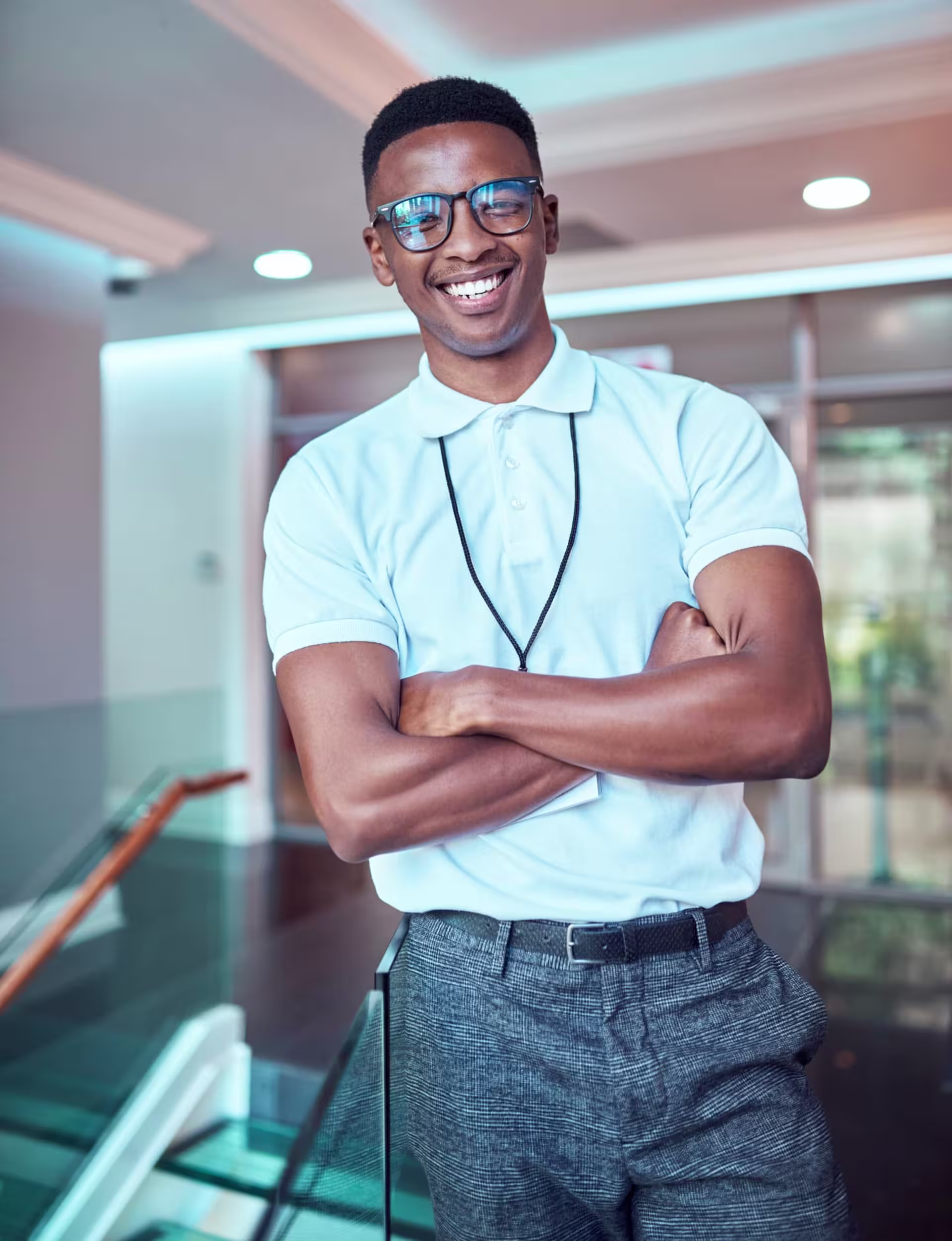 Student in healthcare attire smiling and standing in a modern educational setting, representing coursework in a public health degree program.