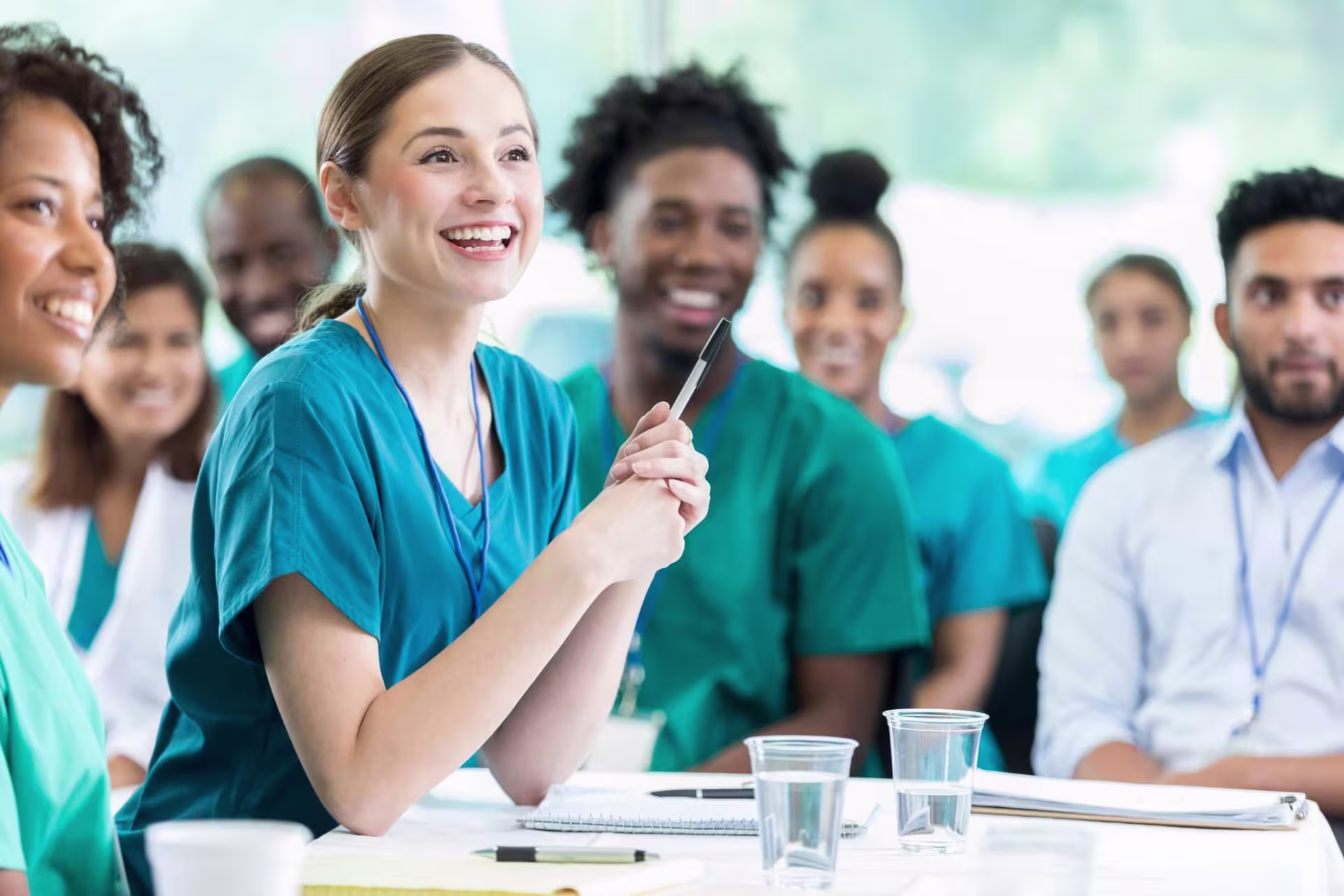 Group of diverse students in healthcare attire attending a classroom session in a public health degree program.