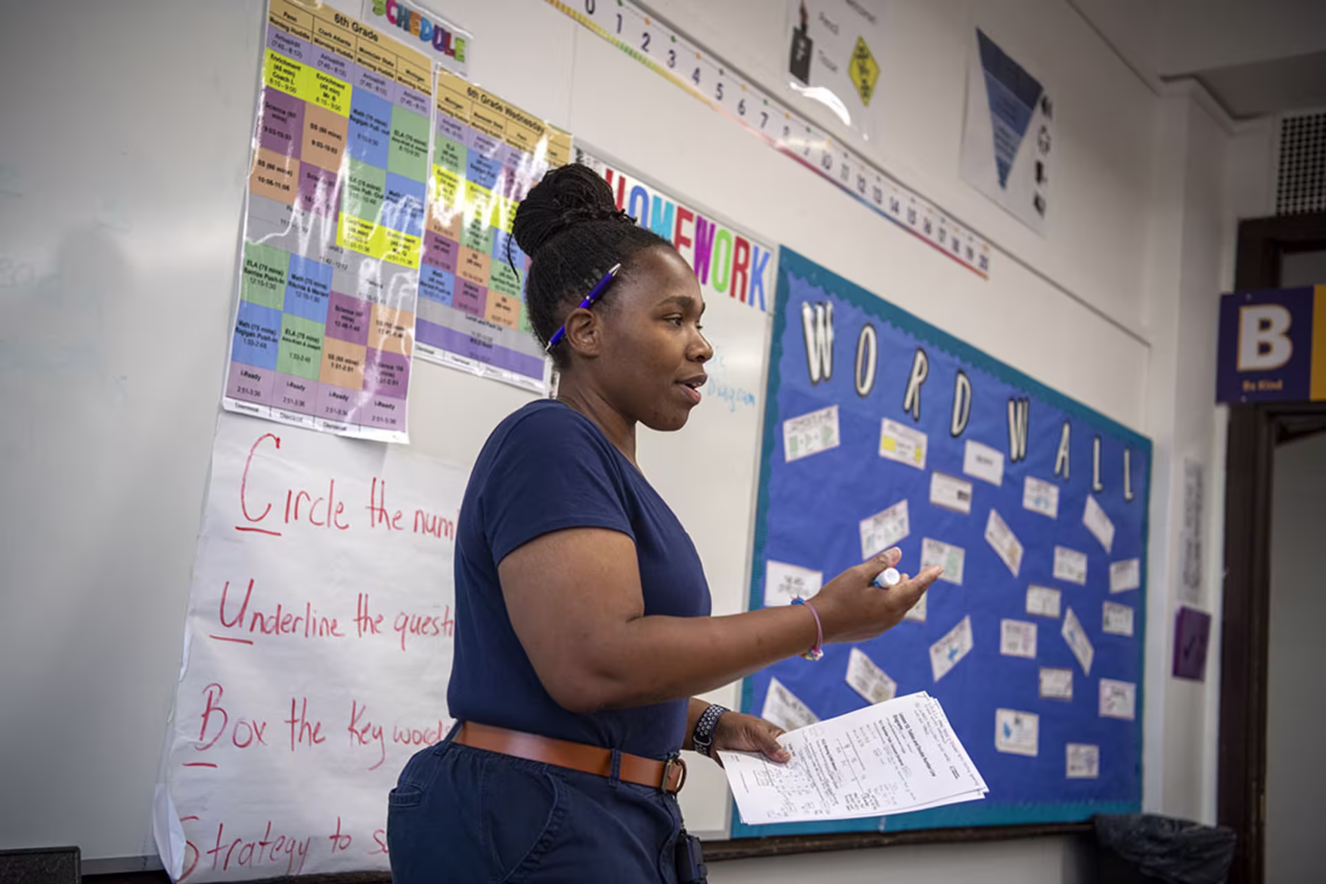 Female educator teaching in front of classroom by whiteboard