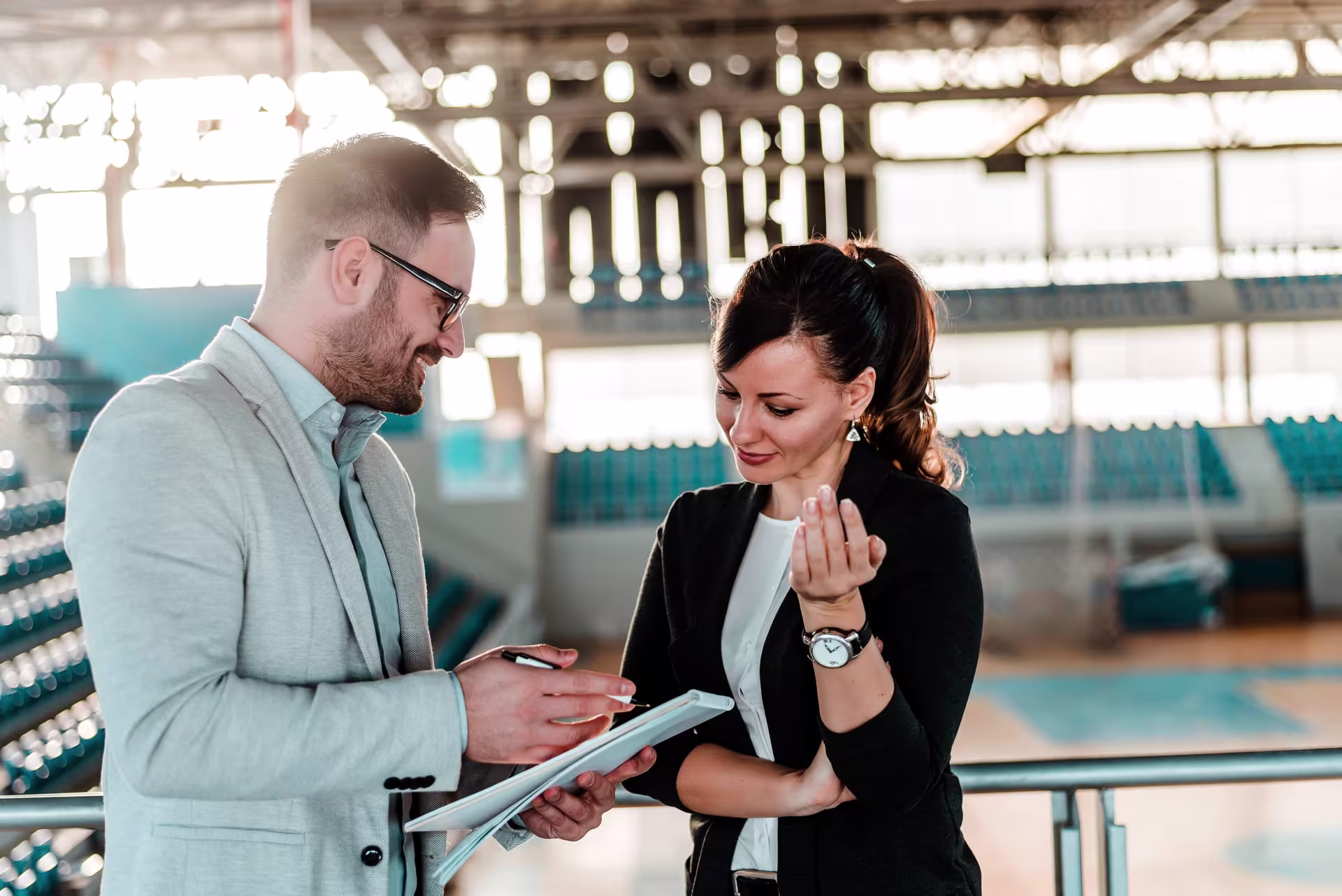 Two sports business professionals talking strategy in a basketball gym.