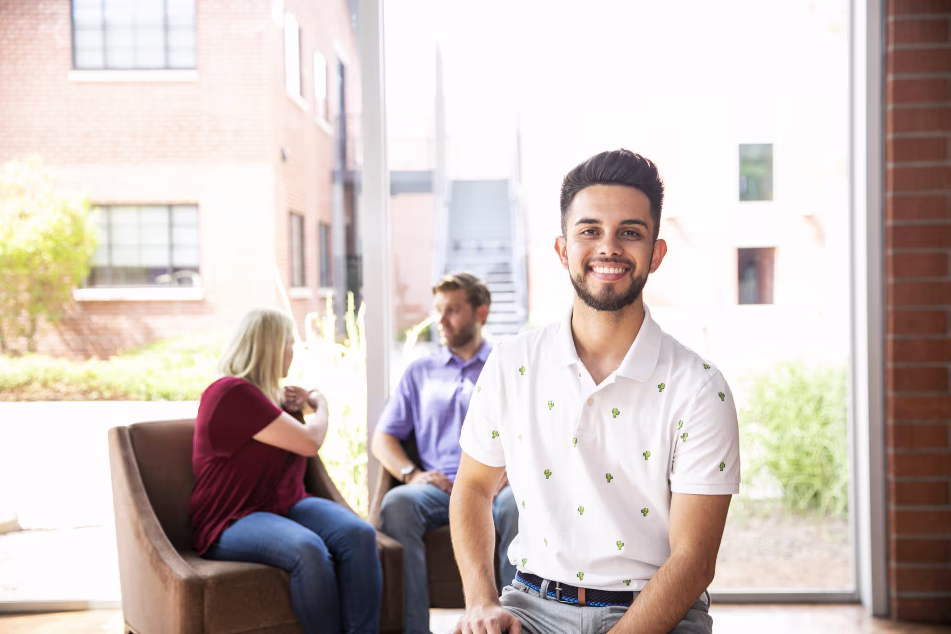 Headshot of male humanities student smiling in front of peers in study hall